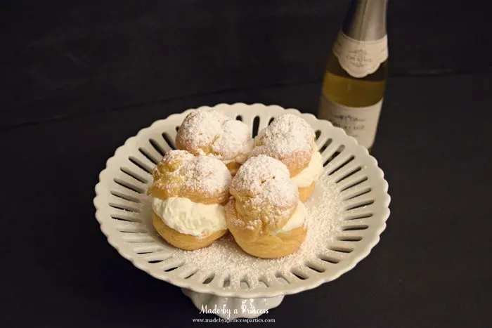 easy-champagne-cream-puffs-recipe-with-powdered-sugar-on-a-cake-stand