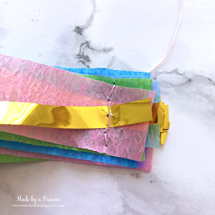 unicorn princess party hat idea tutorial layer crepe paper and gold fringe bring threaded needle through all layers and sew together