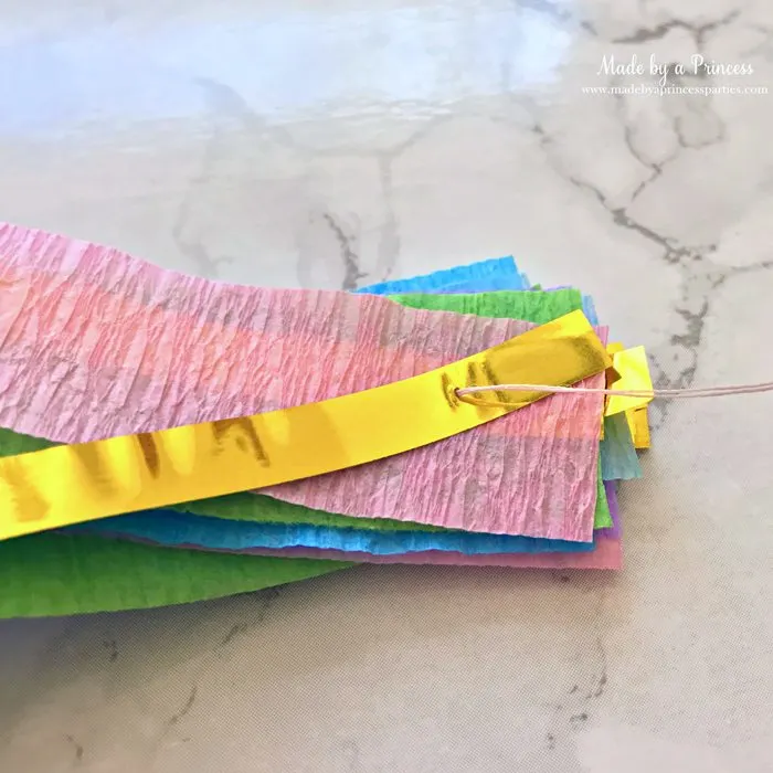 unicorn princess party hat idea tutorial layer crepe paper and gold fringe bring threaded needle through all layers